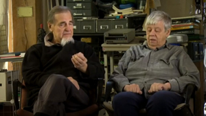 Two elderly people sitting in chairs in a room.