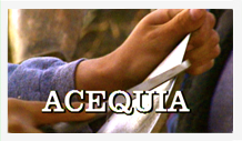 A person cutting a piece of paper with the word acequia.
