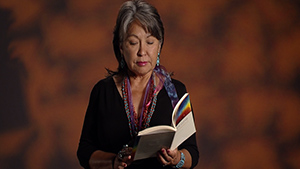 A woman reading a book in front of a dark background.