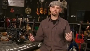 A man standing in front of a guitar rack.