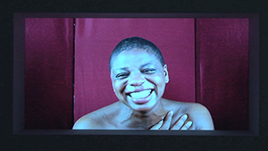 An image of a woman smiling in front of a screen.