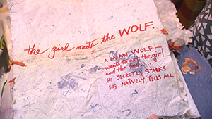 A woman is holding a piece of paper that says the girl met the wolf.