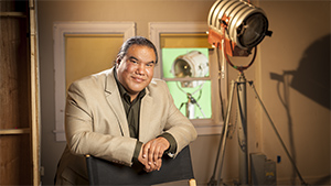 A man sitting in a chair in front of a green screen.