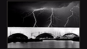 Lightning over a bridge in black and white.
