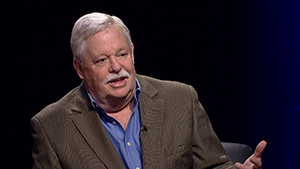 A man with a mustache is sitting in a chair.