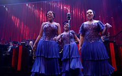 A group of women in blue dresses singing on stage.