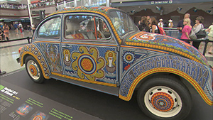 A vw beetle is on display in a museum.