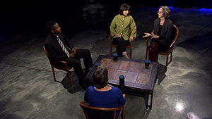 A group of people sitting around a table on a stage.