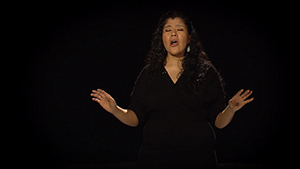 A woman is singing in a dark room.