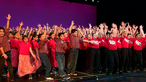 A group of people in red shirts on stage.