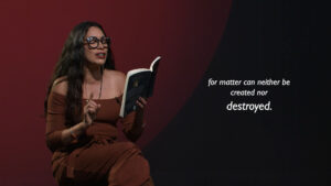 A woman in glasses and a brown outfit reads from a book, gesturing with her hand. White text beside her reads, "for matter can neither be created nor destroyed.