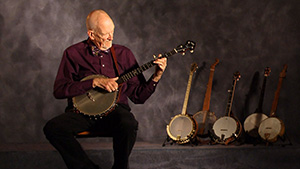 A man sitting in front of a group of banjos.