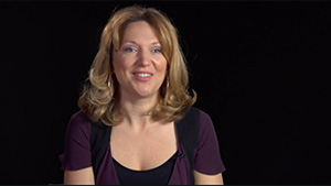 A woman is smiling in front of a black background.