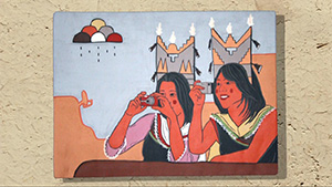 A painting of two native women sitting at a table.