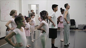 A group of children are standing in a ballet class.