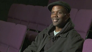 A man in a black hat sitting in a purple chair.