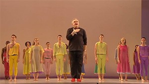 A man standing on stage with a group of dancers.