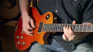 A man playing an electric guitar in a recording studio.