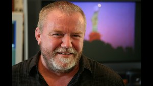 A man with a beard in front of a tv.