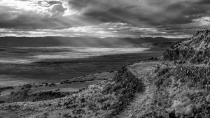 A black and white photo of a valley with sun rays.