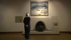 A woman looking at a painting in a museum.