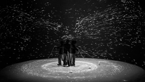 A black and white photo of a group of people standing on a circular platform.