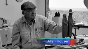 A black and white photo of an old man holding a sculpture.