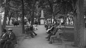 A group of people sitting on benches in a park.