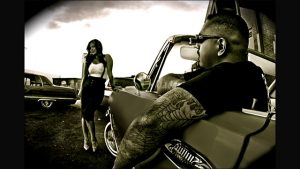 A man with tattoos and a woman sitting in a car.