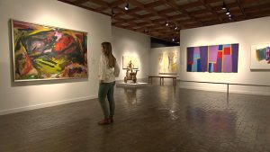 A woman looking at paintings in an art gallery.