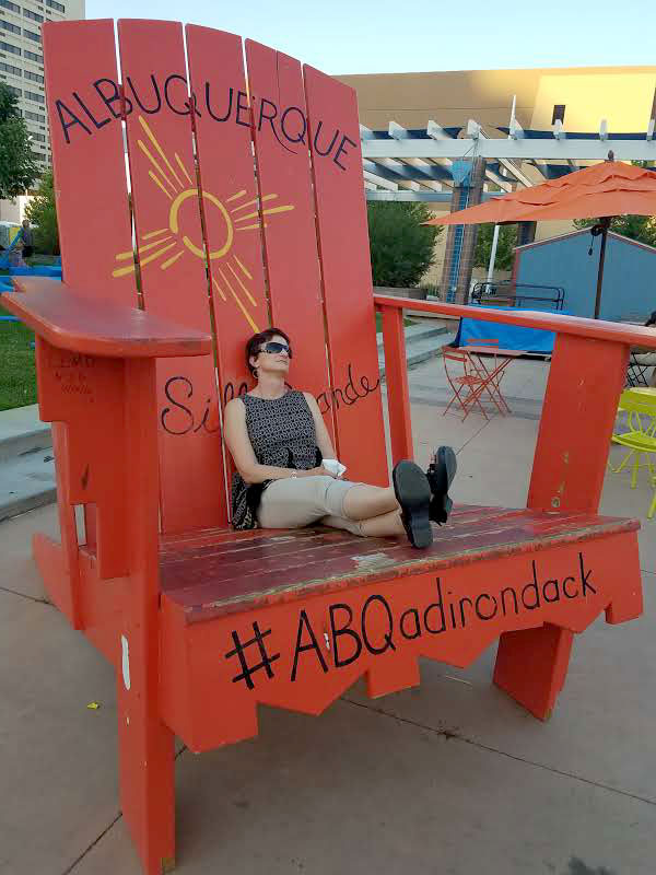 A woman sitting in a red adirondack chair.