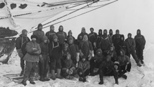 A group of people posing in front of a ship.