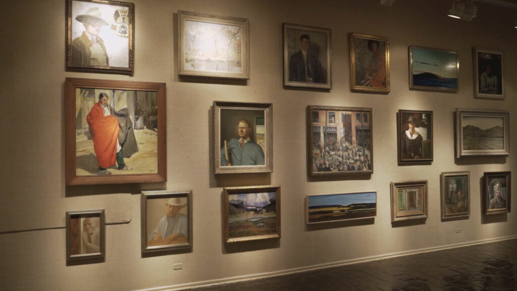 A gallery wall dimly lit with portraits hanging on it