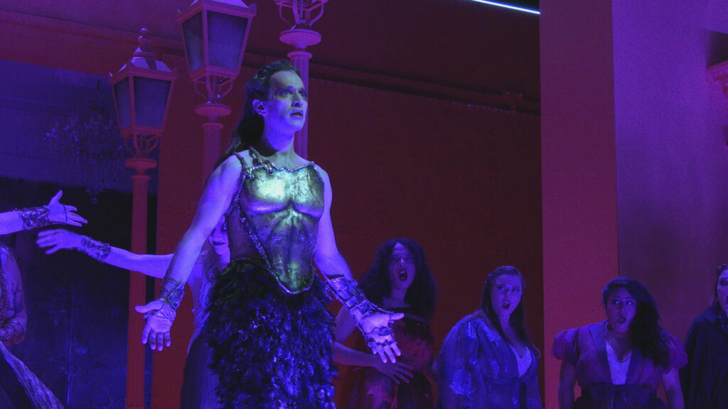 An actor in costume performing in blue lighting