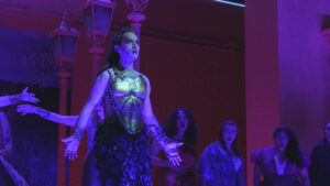 An actor in costume performing in blue lighting