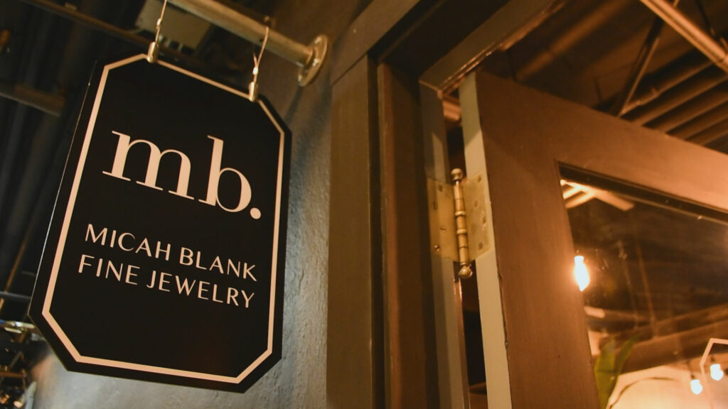 A hanging business sign for Micah Blank Fine Jewelry