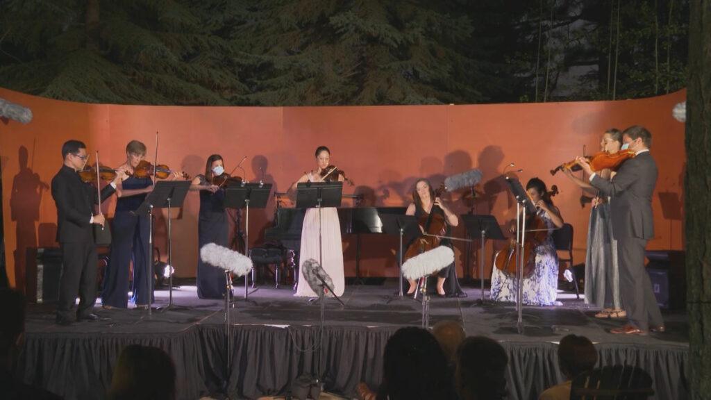 A group of musicians performing outside on a stage