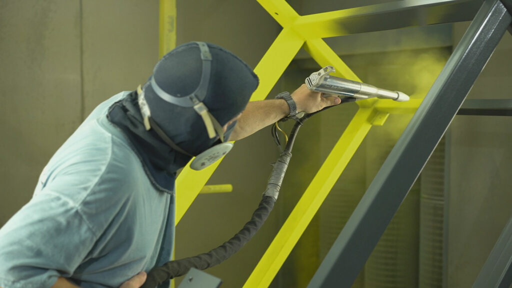 A person spraying paint onto a metal structure