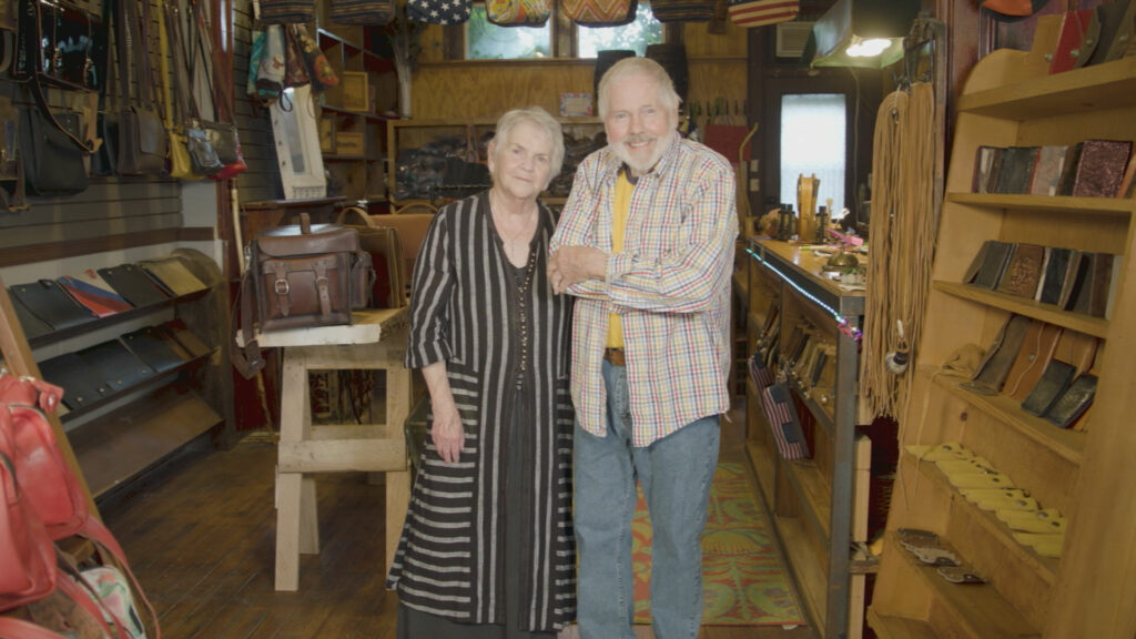 A couple stands together in a shop selling leather goods