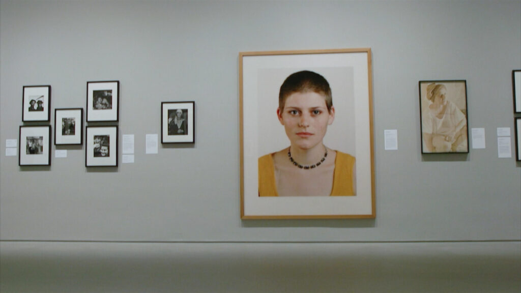 An art gallery wall with portraits of people hanging