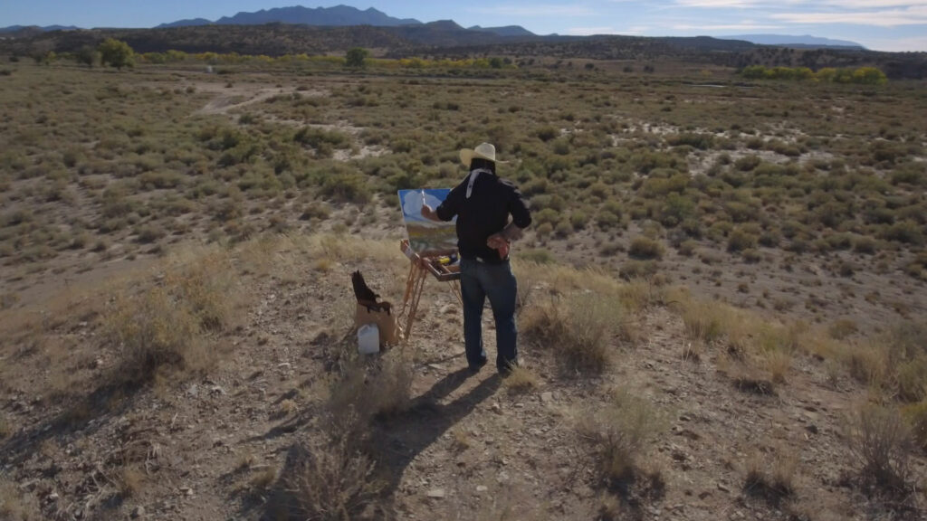 A person painting in the middle of the New Mexico desert