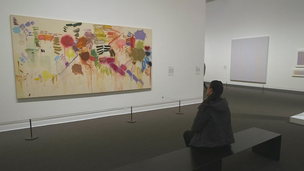 A person sitting down on a bench looking at abstract art