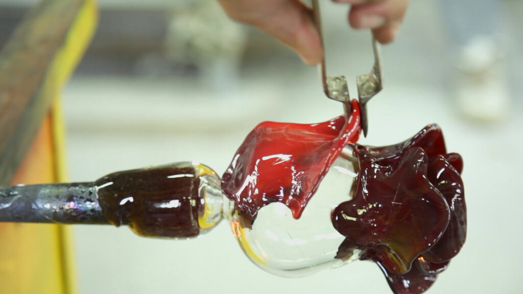 Someone melting glass into the shape of a rose