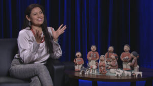 Kathleen Wall talking with her hands out stretched during an interview sitting next to her nativity scene.