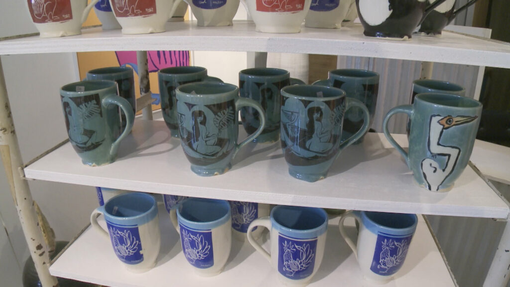 Shelves of brightly colored ceramic mugs.