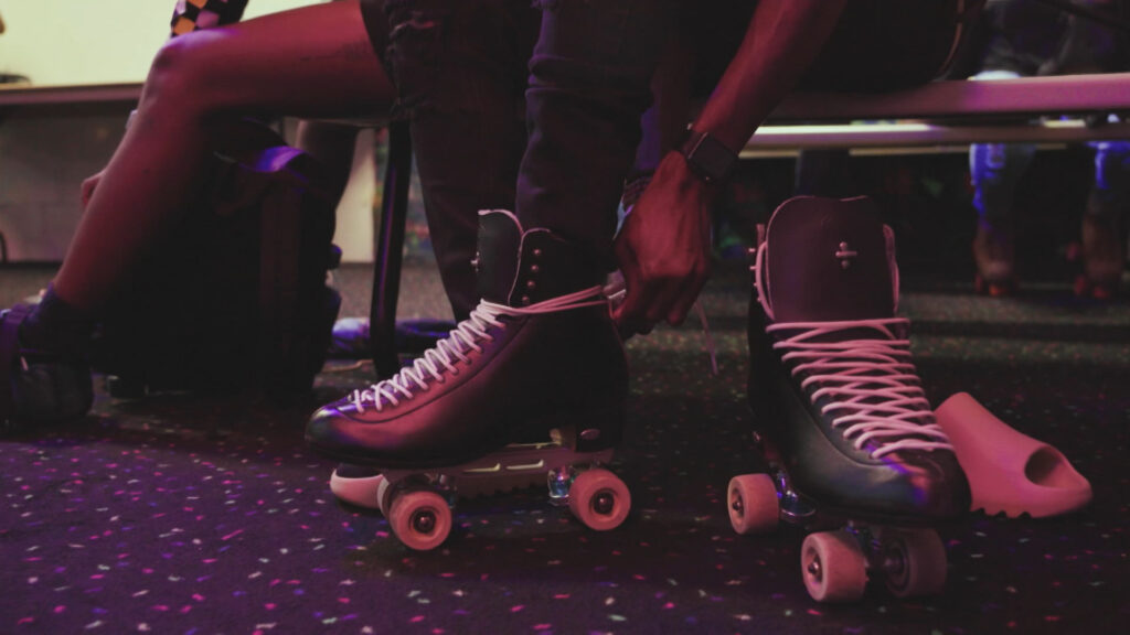 People putting on roller skates illuminated by pink lights.