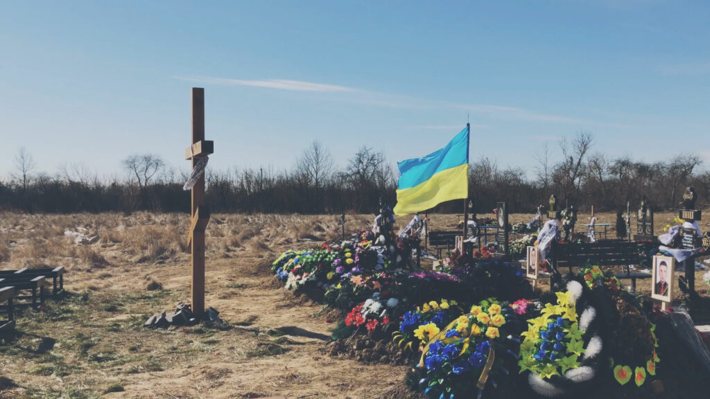 A cemetary with a Ukraine flag flying.