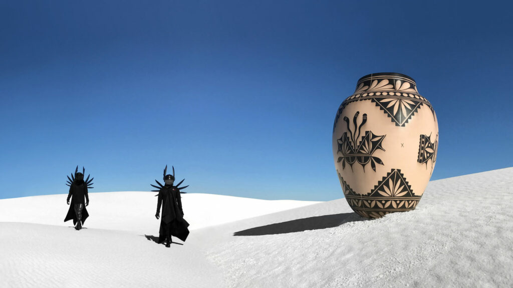A traditional piece of pottery in the white sands with two people dressed in all black costumes.