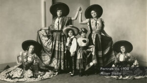 A group of people posing for a photo wearing similar skirts and matching wide-brimmed hats.