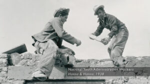 A 1938 black and white photograph of two people moving bricks.